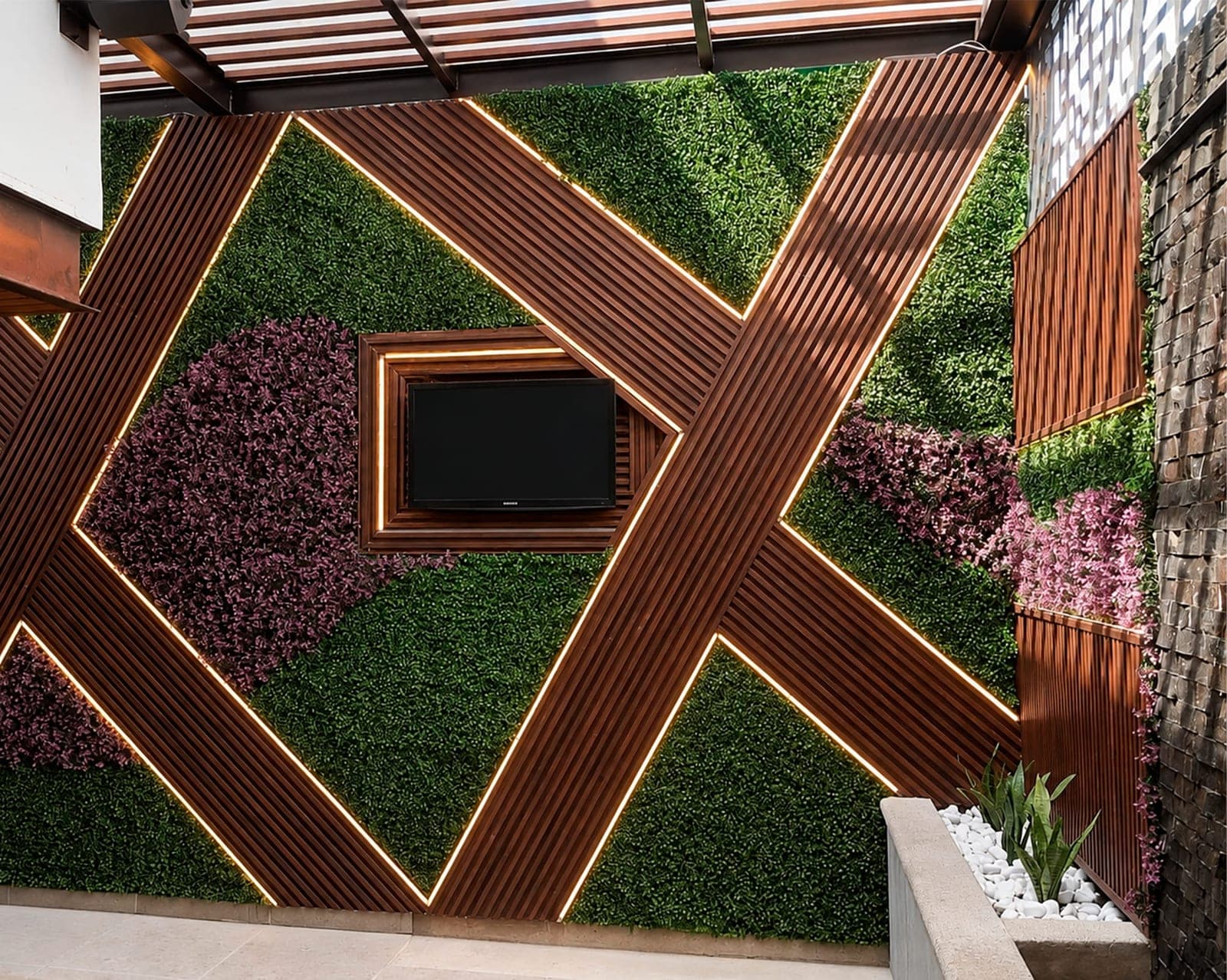 Muro decorativo con follaje sintético, lambrín de madera iluminado y pantalla exterior
