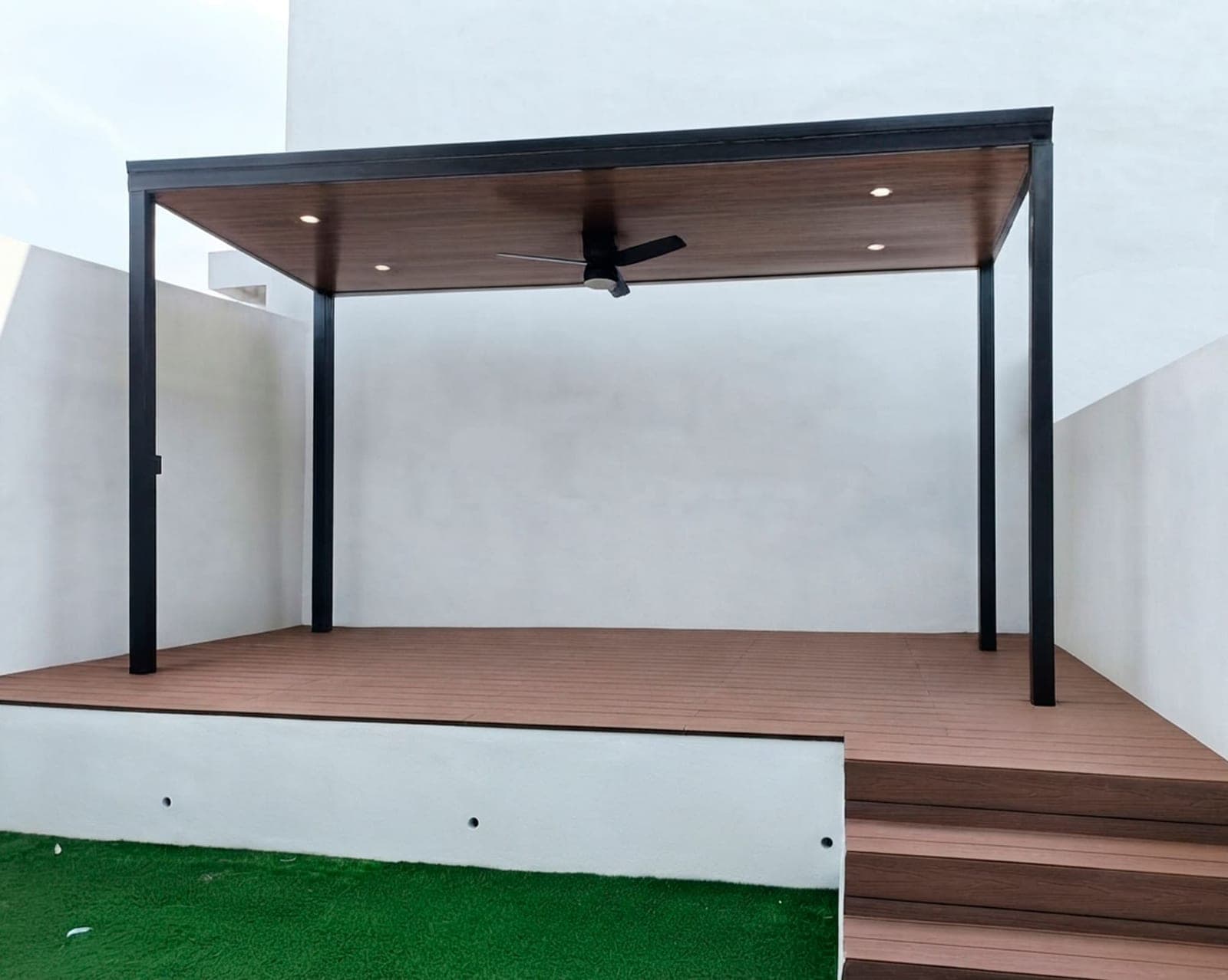 Pérgola metálica con plafón de madera sobre un deck, en una terraza blanca