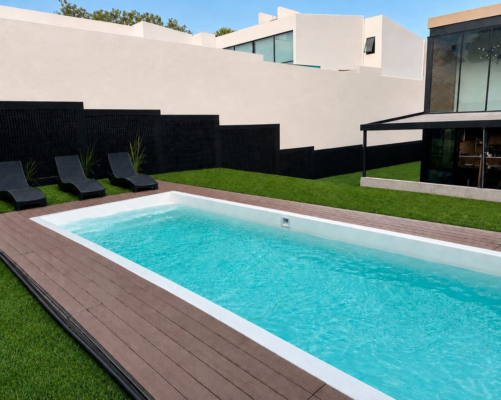 Piscina de fibra de vidrio con deck de madera, camastros y pasto sintético