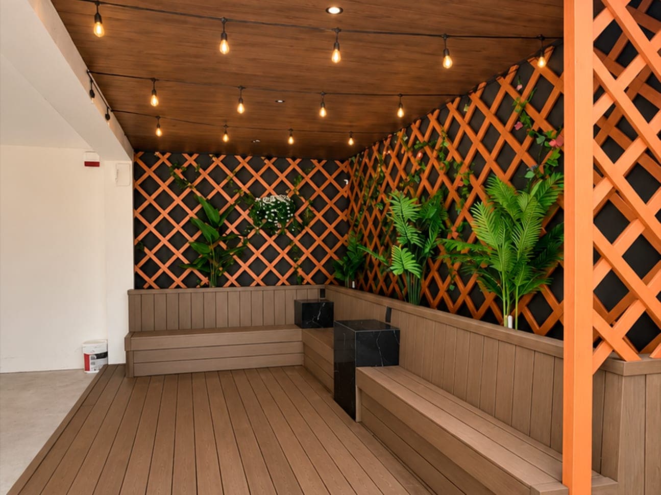 Terraza terminada con deck, bancas empotradas, celosía de madera y luces colgantes