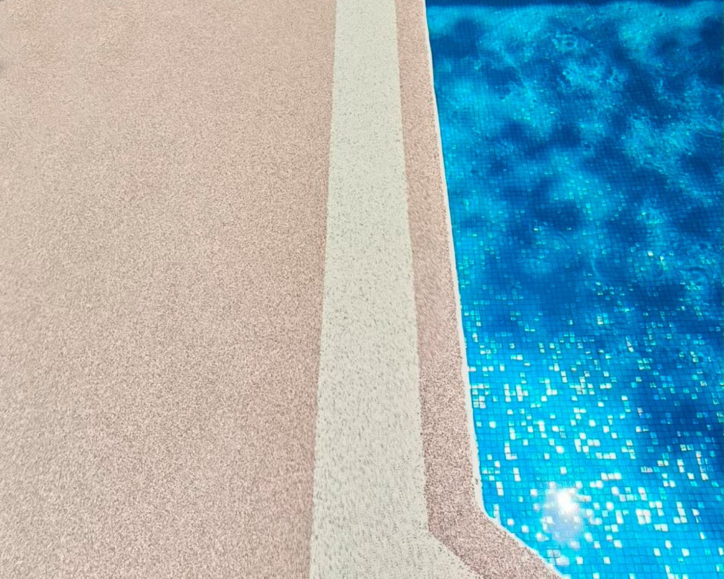 Piso de granito granulado en tono rosado junto al borde de una piscina